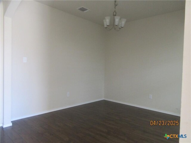 spare room with dark wood-style flooring, a chandelier, visible vents, baseboards, and arched walkways