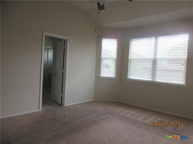 empty room with ceiling fan, vaulted ceiling, carpet, and baseboards
