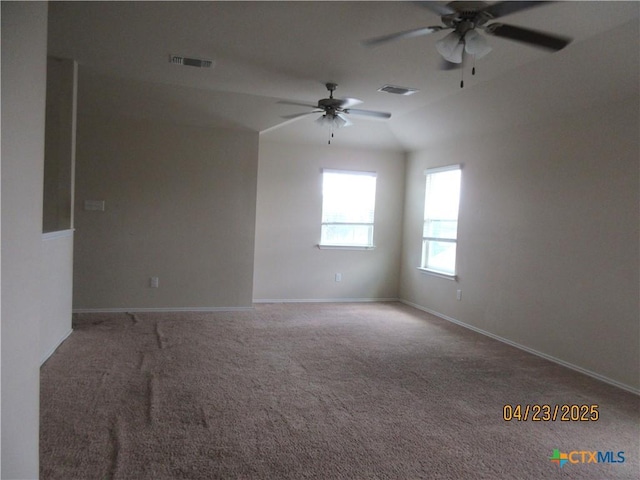 empty room featuring carpet, visible vents, ceiling fan, and vaulted ceiling