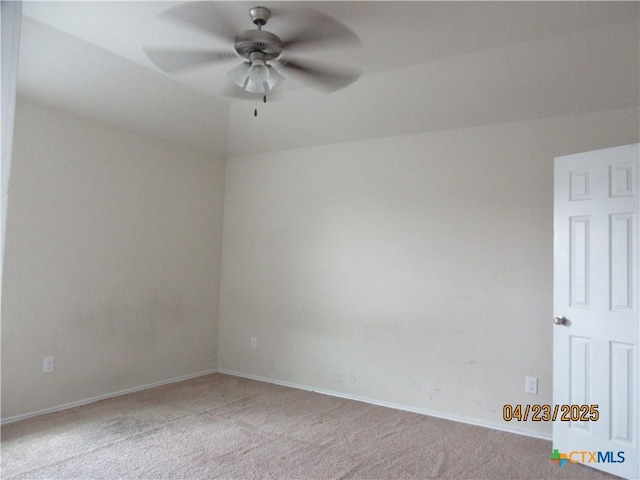 spare room with light colored carpet, a ceiling fan, and baseboards