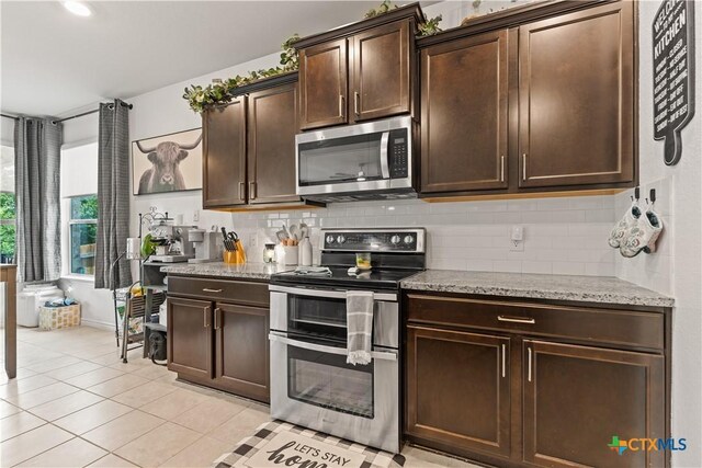 5998 Galveston Rd, Belton, TX 76513 - kitchen with appliances with stainless steel finishes, dark brown cabinetry, decorative backsplash, light tile patterned floors, and light stone countertops