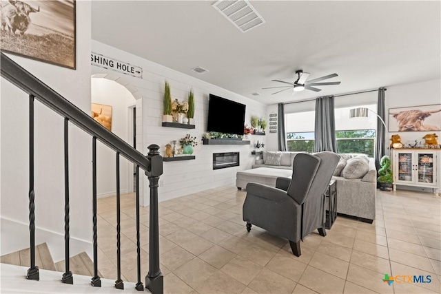 5998 Galveston Rd, Belton, TX 76513 - tiled living room with a glass covered fireplace, ceiling fan, stairs, and arched walkways