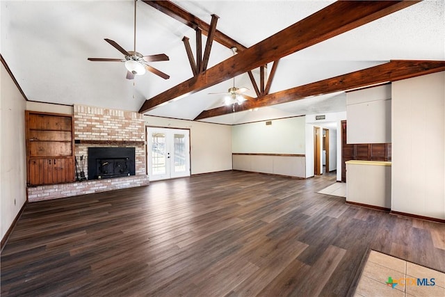 unfurnished living room featuring a brick fireplace, ceiling fan, lofted ceiling with beams, french doors, and wood finished floors