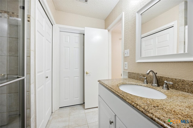 bathroom featuring vanity, tile patterned floors, a textured ceiling, and an enclosed shower