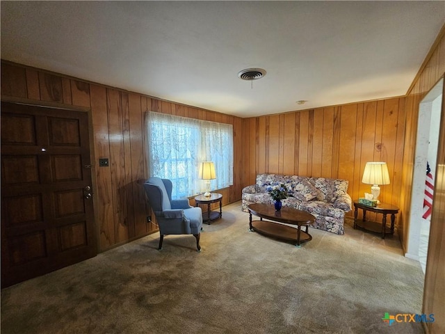 carpeted living area featuring visible vents and wooden walls