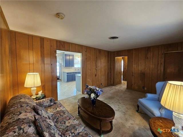 living area featuring visible vents, light colored carpet, and wooden walls