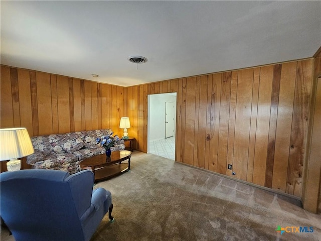 living area with visible vents, carpet floors, and wooden walls