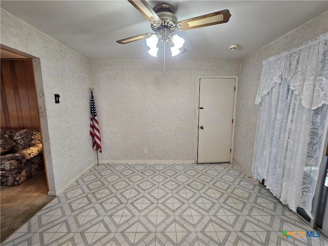 spare room with baseboards, light floors, ceiling fan, and wallpapered walls