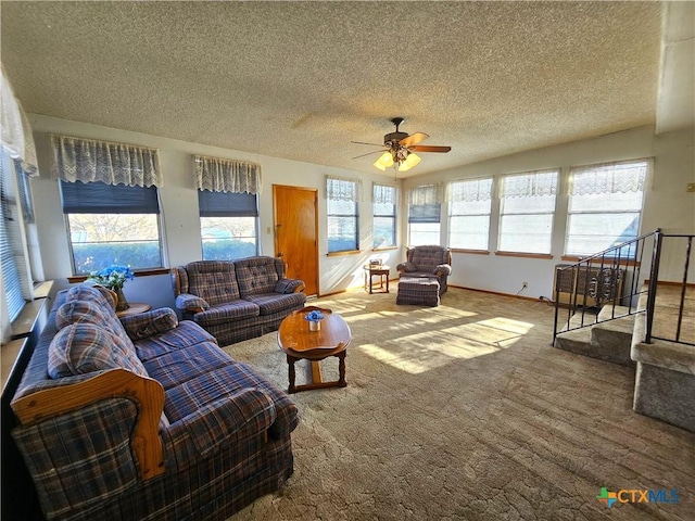 living area featuring carpet flooring, a ceiling fan, baseboards, and a textured ceiling