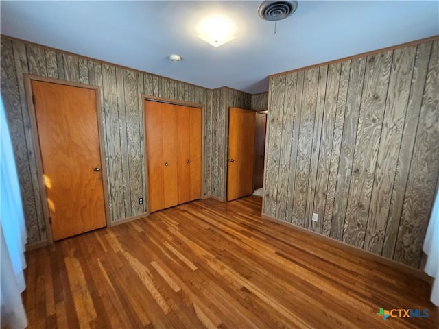 unfurnished bedroom with visible vents and wood finished floors