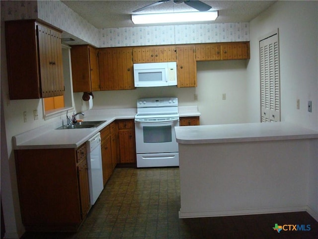 kitchen with sink, white appliances, kitchen peninsula, and a textured ceiling