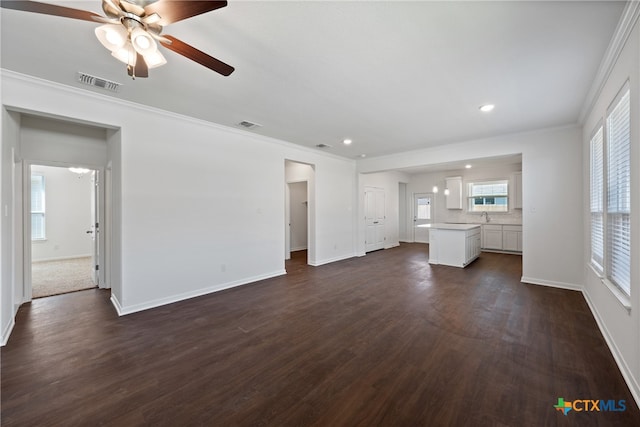 unfurnished living room featuring ornamental molding, ceiling fan, sink, and dark hardwood / wood-style floors