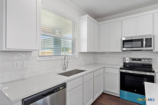 kitchen featuring sink, appliances with stainless steel finishes, crown molding, white cabinets, and dark wood-type flooring