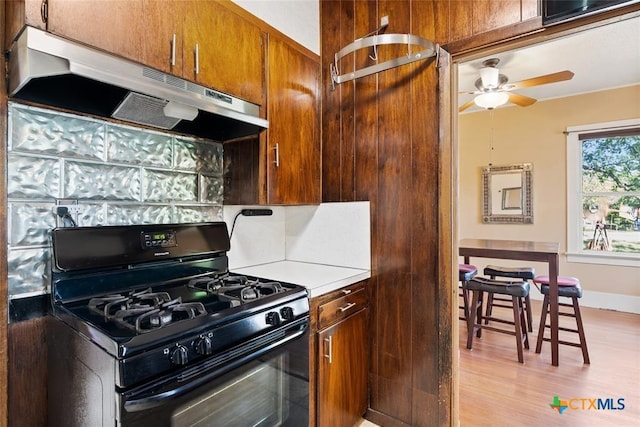 215 Taylor Rd, Elgin, TX 78621 - kitchen with black gas range, ceiling fan, light countertops, under cabinet range hood, and light wood finished floors