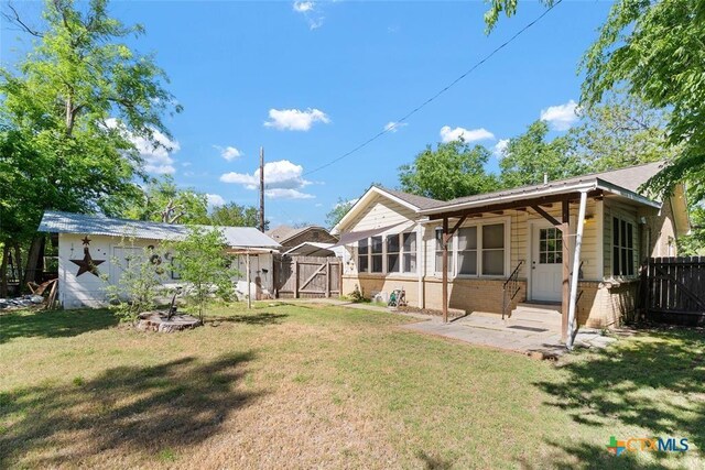 215 Taylor Rd, Elgin, TX 78621 - back of house featuring fence, a gate, a lawn, and brick siding