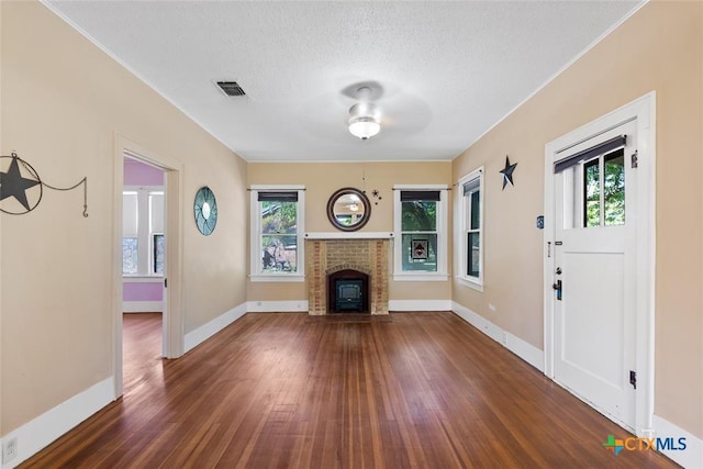 215 Taylor Rd, Elgin, TX 78621 - unfurnished living room with a textured ceiling, visible vents, a fireplace, wood finished floors, and baseboards
