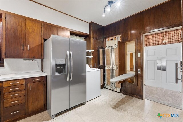 215 Taylor Rd, Elgin, TX 78621 - kitchen with light countertops, washer / dryer, wood walls, and stainless steel fridge with ice dispenser