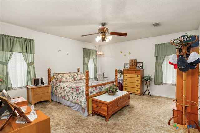 carpeted bedroom with ceiling fan and a textured ceiling