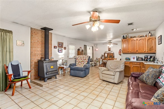 living room featuring a textured ceiling, a wood stove, and ceiling fan