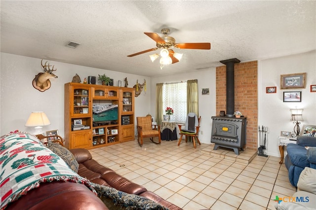 tiled living room with a wood stove, ceiling fan, and a textured ceiling