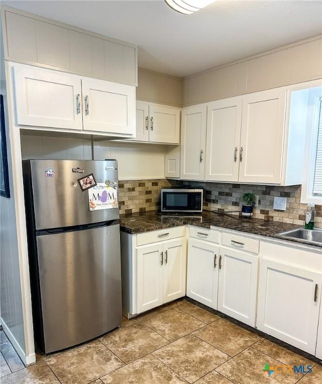 111 Kenilworth Glen St, Victoria, TX 77904 - kitchen with appliances with stainless steel finishes, tasteful backsplash, white cabinets, a sink, and dark stone countertops