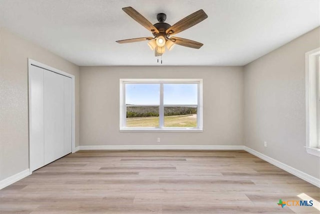 unfurnished bedroom with a ceiling fan, baseboards, light wood-type flooring, and a closet