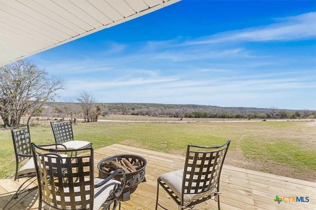 view of patio / terrace featuring a deck, a rural view, and an outdoor fire pit