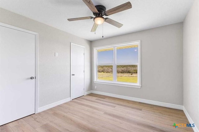 unfurnished bedroom featuring a ceiling fan, baseboards, and light wood-type flooring