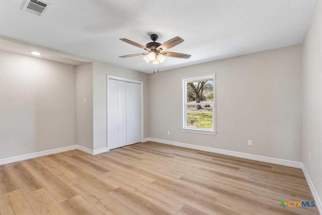 unfurnished bedroom featuring light wood-style flooring, baseboards, visible vents, and a closet