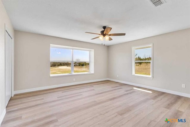 empty room with visible vents, ceiling fan, baseboards, and light wood-style floors