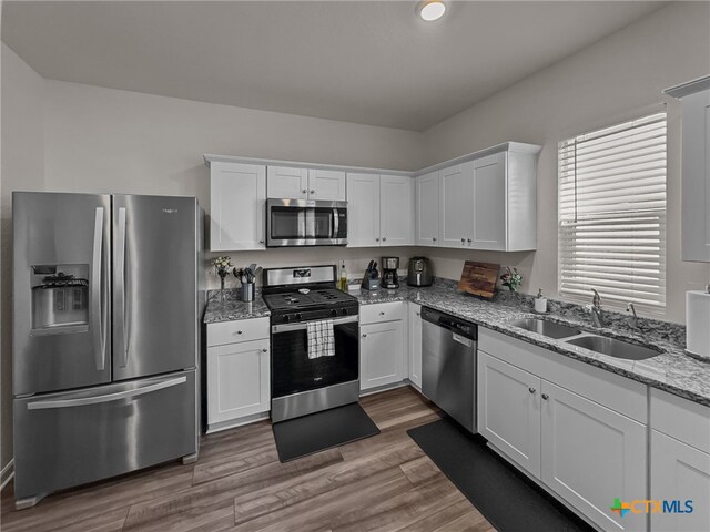 kitchen with dark wood-type flooring, white cabinets, sink, and stainless steel appliances