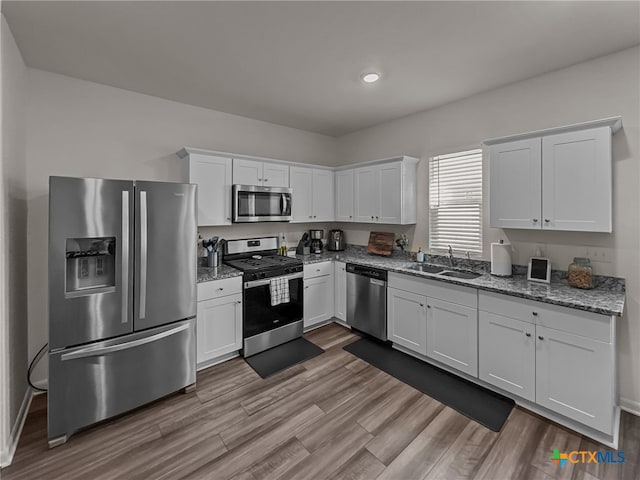 kitchen featuring white cabinets, light wood-type flooring, appliances with stainless steel finishes, and sink