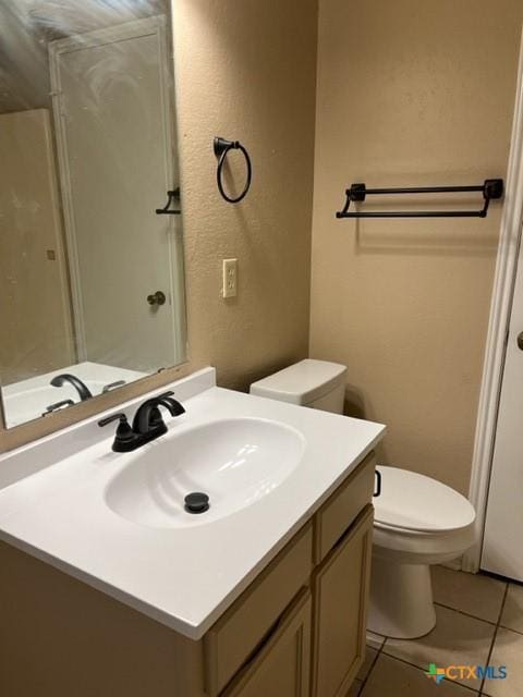 bathroom with toilet, vanity, and tile patterned floors