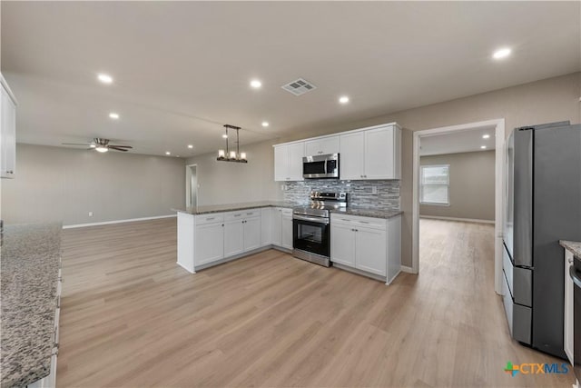 kitchen featuring pendant lighting, white cabinetry, kitchen peninsula, and appliances with stainless steel finishes