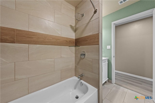 bathroom featuring wood-type flooring, vanity, and tiled shower / bath