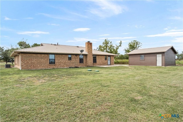 back of property with central AC unit, an outdoor structure, and a yard