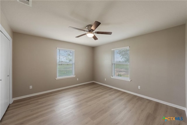 empty room featuring a textured ceiling, light hardwood / wood-style flooring, and ceiling fan