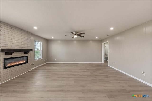 unfurnished living room with a fireplace, light hardwood / wood-style flooring, and ceiling fan