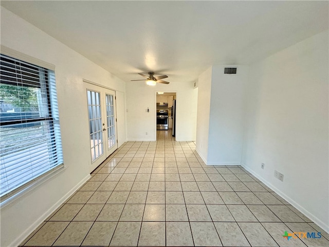 empty room with ceiling fan, french doors, light tile patterned flooring, and a healthy amount of sunlight