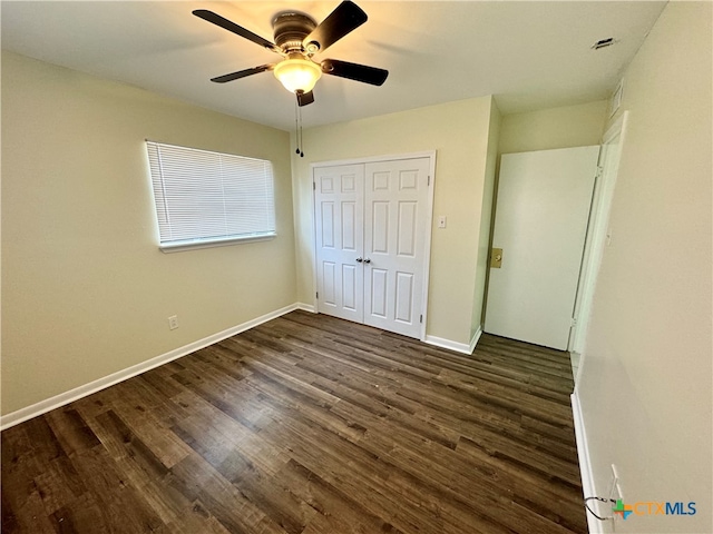 unfurnished bedroom featuring ceiling fan, dark hardwood / wood-style floors, and a closet