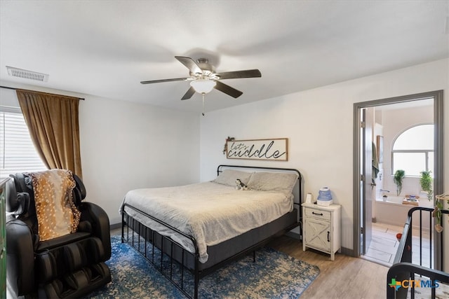 bedroom with multiple windows, ceiling fan, connected bathroom, and hardwood / wood-style flooring