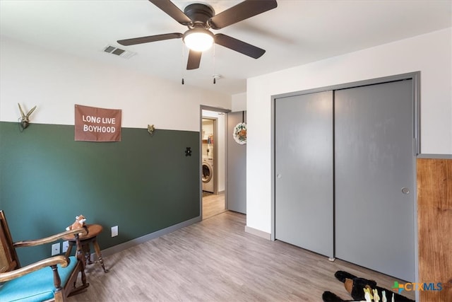 living area featuring light wood-type flooring, ceiling fan, and washer / dryer