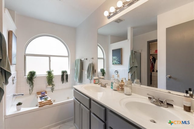 bathroom with vanity, a washtub, and decorative backsplash