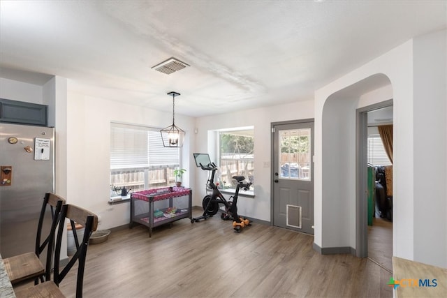 workout room featuring an inviting chandelier and wood-type flooring