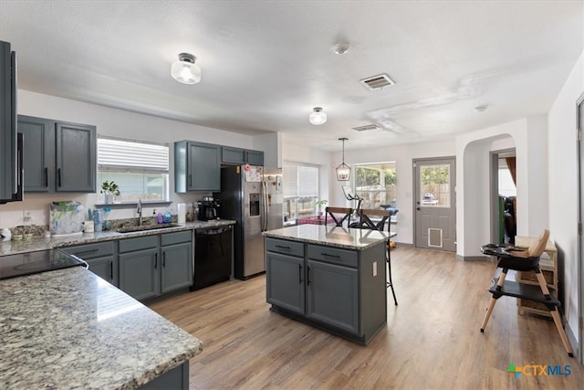 kitchen featuring black dishwasher, decorative light fixtures, sink, and a kitchen island