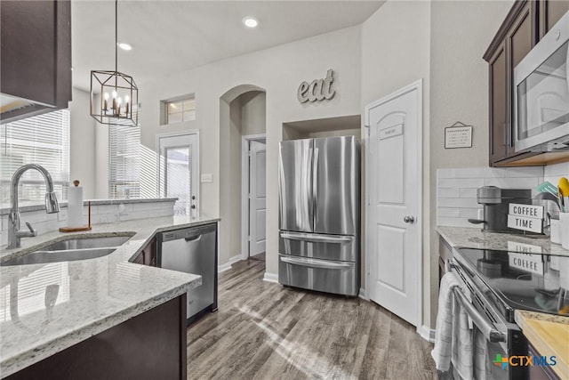 kitchen featuring light stone countertops, appliances with stainless steel finishes, dark hardwood / wood-style flooring, dark brown cabinetry, and sink