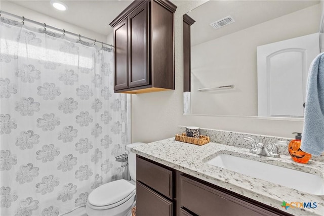 bathroom with curtained shower, vanity, and toilet