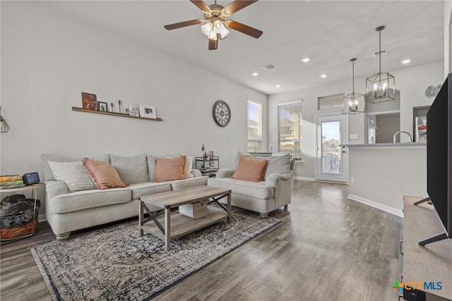 living room with hardwood / wood-style floors and ceiling fan with notable chandelier