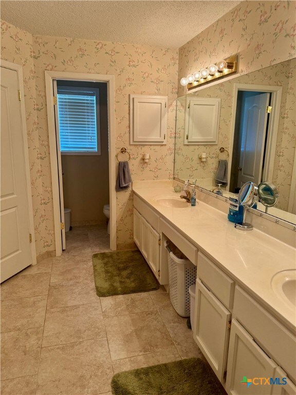 bathroom with vanity, tile patterned floors, a textured ceiling, and toilet