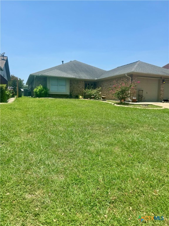 ranch-style house featuring a garage and a front lawn